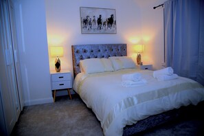 Un dormitorio con una cama grande, dos mesitas de noche, un cabecero y un cuadro en la pared.