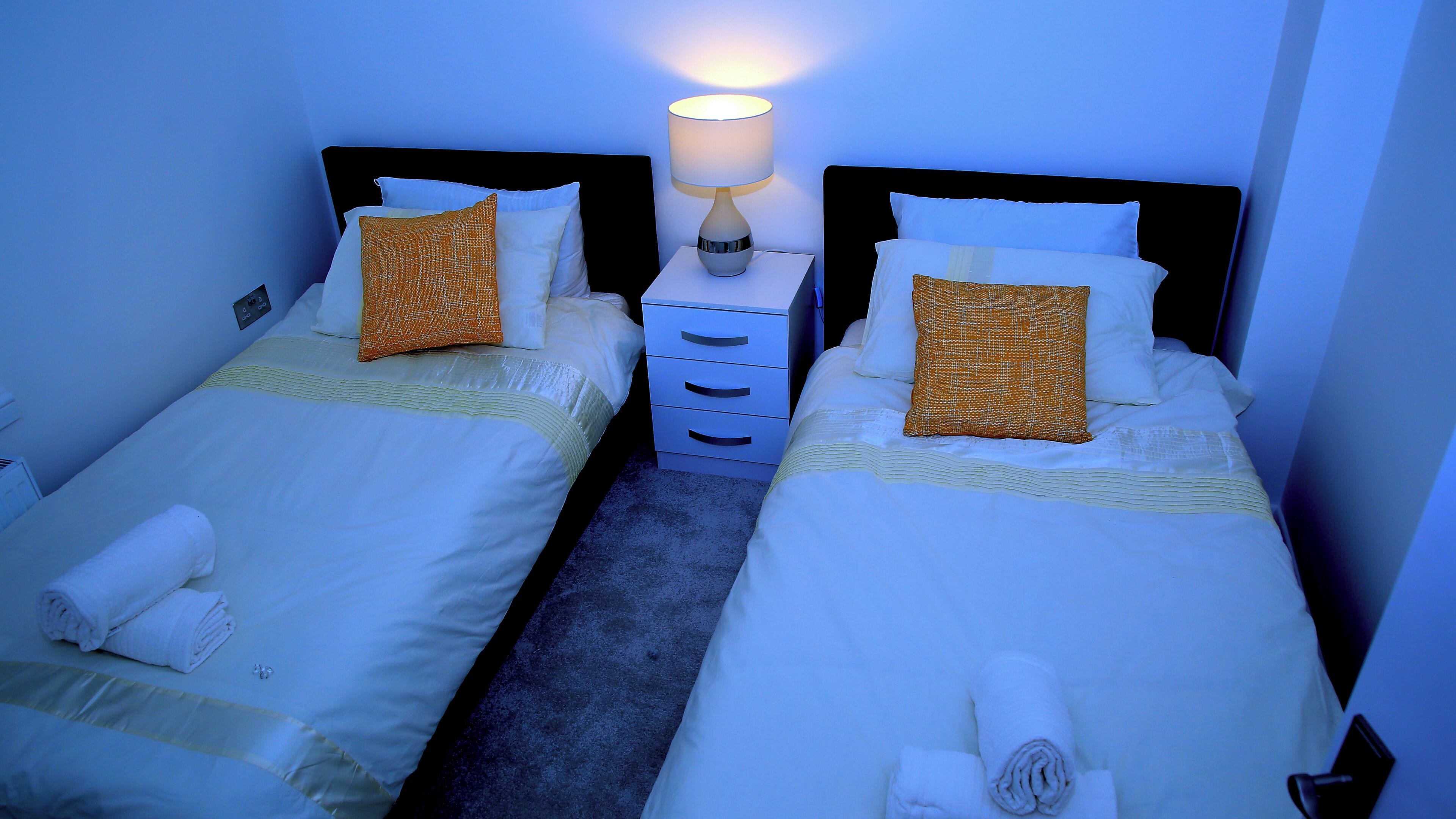 A twin room with two beds, a nightstand, and a lamp.