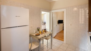 A compact kitchen with a Bosch refrigerator, a dining table with chairs, and a breakfast setup. - San Nicolo dei Vecchi Casa  by CorfuEscapes (Corfu)
