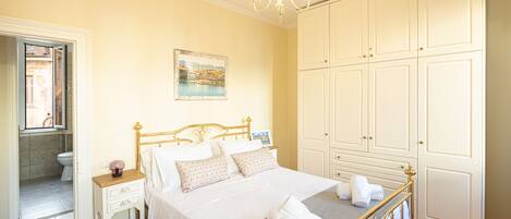 A bedroom with a bed, bedside table, nightstand, and wardrobe.