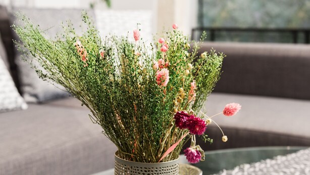 A table with a woven table runner, a vase with flowers, and a decorative mug. - Eden Apartments  by CorfuEscapes (Corfu)