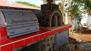 A barbecue grill with a stone oven and a red tiled countertop.