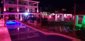 A two-story building with a swimming pool, outdoor seating, and a well-lit patio area. - Villa de Colores 3 Rooms 5 King Beds (Sosúa)