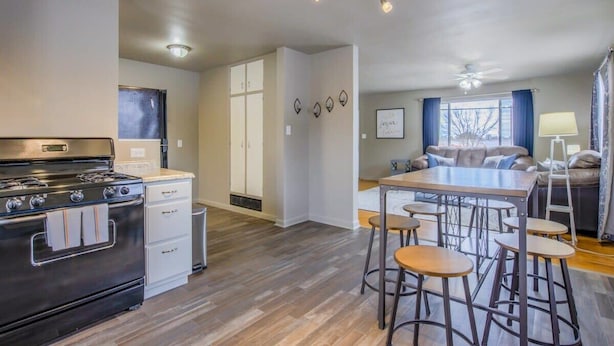 A modern kitchen with a stove, white cabinets, and a bar area with stools.