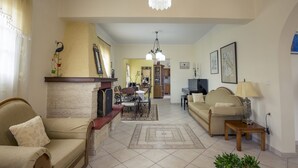 A living room with a sofa, a coffee table, and a dining area with a table and chairs. - Villa Southern Comfort by CorfuEscapes (Corfu)