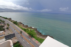 A coastal road with a view of the ocean and a distant city skyline. - Aromas del Mar With Ac and a Sea View (Santo Domingo)
