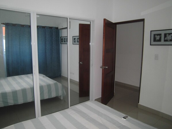 A bedroom with a bed, a sliding glass door, and a wooden door. - Aromas del Mar With Ac and a Sea View (Santo Domingo)
