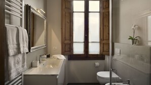 A compact bathroom with a white sink, a toilet, and a shower area.