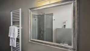 A bathroom with a large mirror, a towel rack, and a shower.