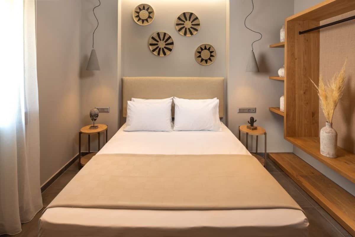 A modern bedroom with a large bed, bedside tables, decorative wall art, and a wooden shelf with decorative items.
