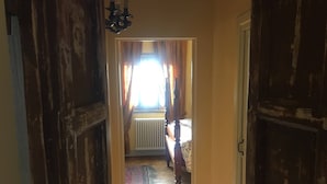 Ein Flur, der zu einem Schlafzimmer mit Bett, Heizkörper und Vorhängen führt.