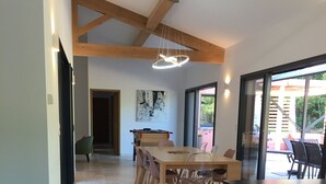 Een moderne keuken met een groot eiland, houten balken en een eethoek met stoelen en een tafel.