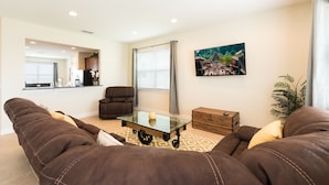 Ein Wohnzimmer mit braunen Ledersofas, einem Glastisch, einer Holzkiste und einem Bild an der Wand.