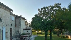 A stone building with a courtyard, outdoor seating, and a tree.