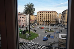 A city street with buildings, a palm tree, and a roundabout. - Family House La Spezia - 5lands By Train (La Spezia)