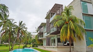 A modern hotel with a pool, palm trees, and a well-maintained lawn. - Magnificent Loft in the Best Area of Acapulco (Acapulco)