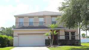 A two-story house with a garage, a small front yard with palm trees, and a clear sky. - Fl Special!! Berkeley Executive Pool 5 Bedroom Villa (Kissimmee)
