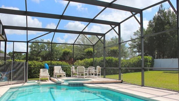 A covered swimming pool with a clear view of the surrounding greenery and a fenced area. - Fl Special!! Berkeley Executive Pool 5 Bedroom Villa (Kissimmee)