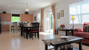 A spacious living area with a dining table, chairs, a sofa, and a coffee table. There is a kitchen area with cabinets and a window with curtains. - Fl Special!! Berkeley Executive Pool 5 Bedroom Villa (Kissimmee)