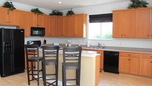 A kitchen with wooden cabinets, a black refrigerator, a microwave, a sink, and a dishwasher. - Fl Special!! Berkeley Executive Pool 5 Bedroom Villa (Kissimmee)