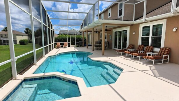 A swimming pool with a glass enclosure, lounge chairs, and a patio area. - 337 Belfry 6 Bedroom Villa by RedAwning (Davenport)