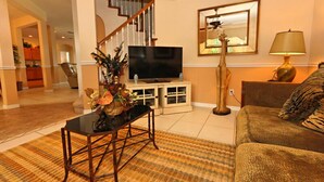 A living room with a sofa, a TV, a lamp, and a staircase. - 337 Belfry 6 Bedroom Villa by RedAwning (Davenport)