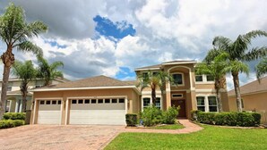 A two-story house with a garage, a driveway, and a well-maintained lawn. - 337 Belfry 6 Bedroom Villa by RedAwning (Davenport)