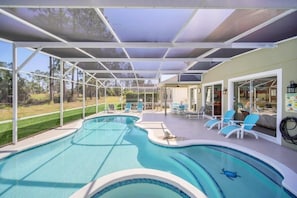 Relax by the pool surrounded by lush greenery and a serene view.