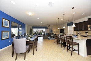 A spacious kitchen with a central island, dark wooden cabinets, and pendant lighting.
