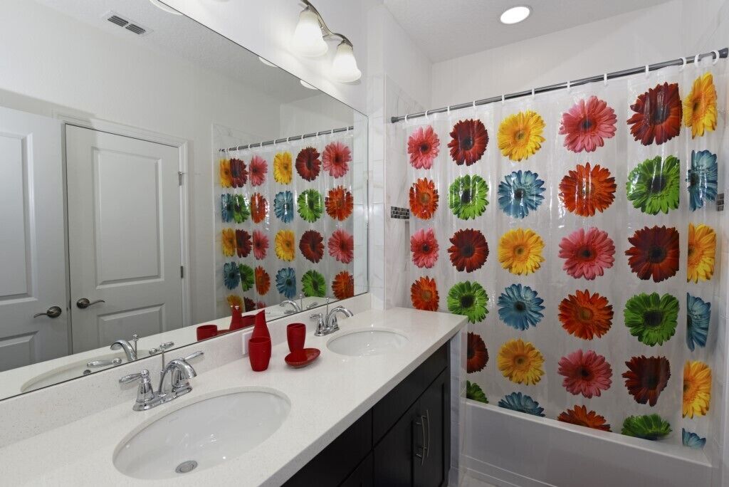 A bathroom with two sinks, a mirror, and a shower curtain with a floral pattern.