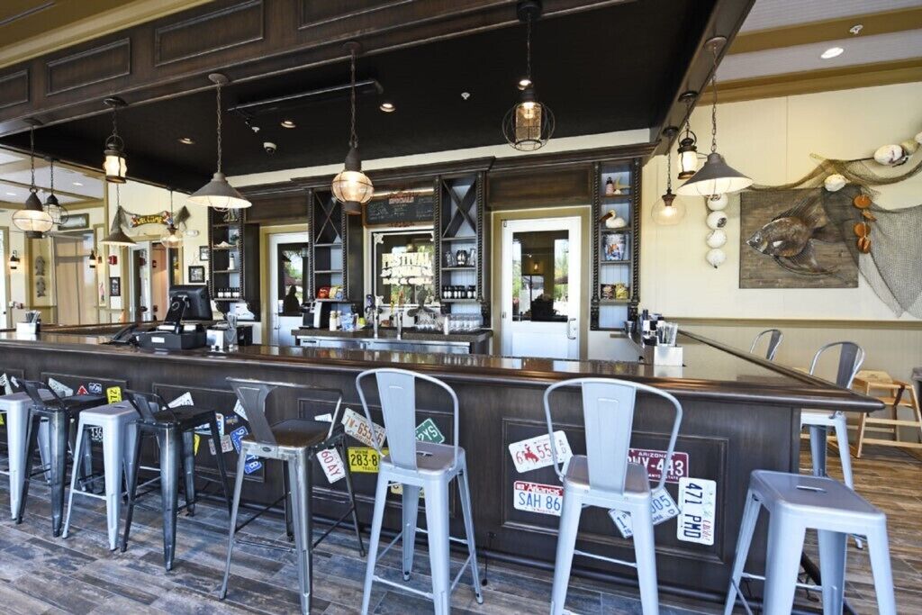 A bar area with metal stools, a counter, and hanging pendant lights.