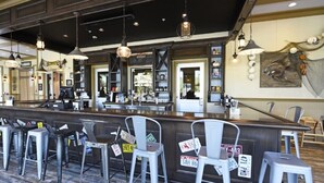 Eine Bar mit Metallhockern, einer Theke und hängenden Pendelleuchten.