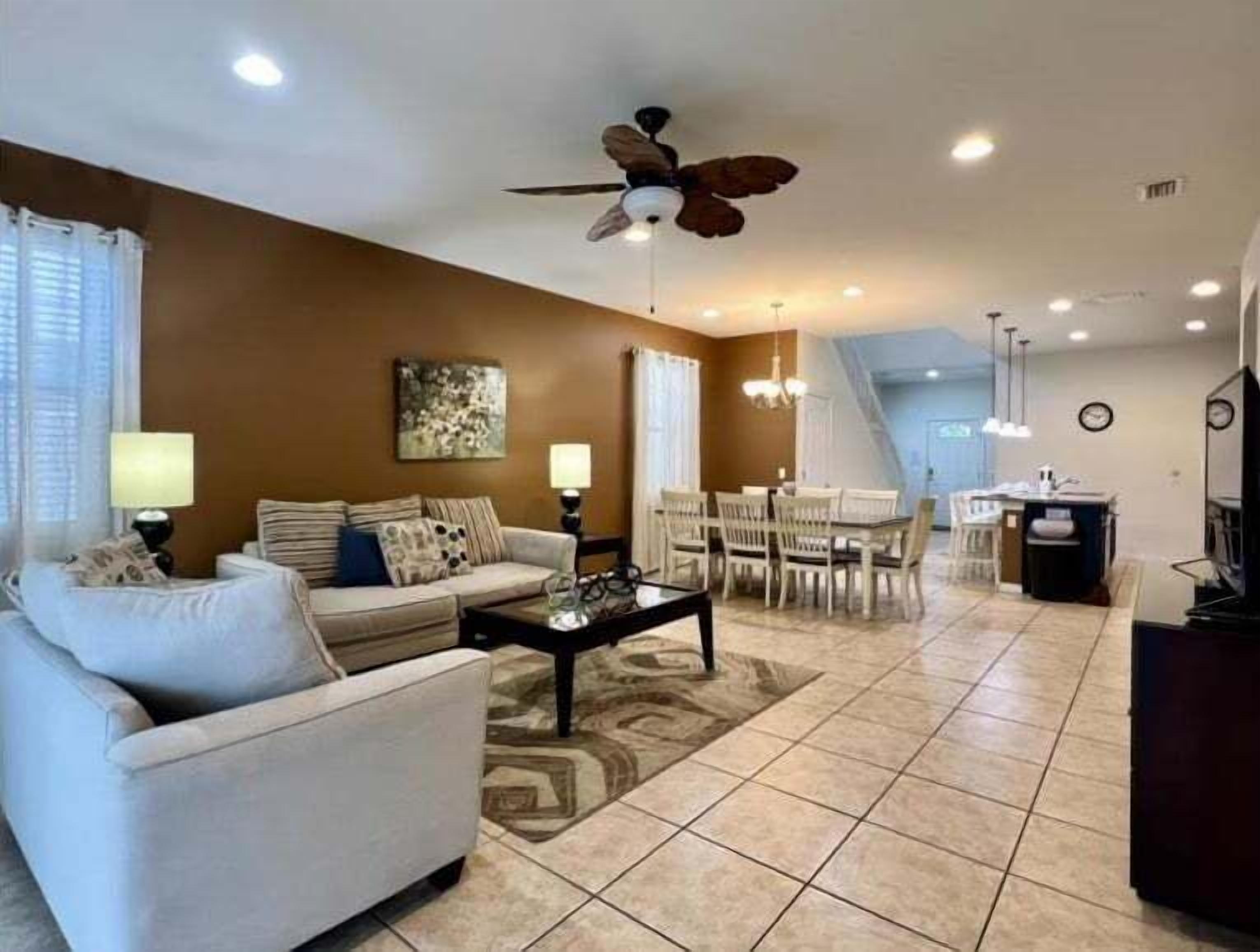 A living room with a sofa, coffee table, and dining area with chairs and a table.