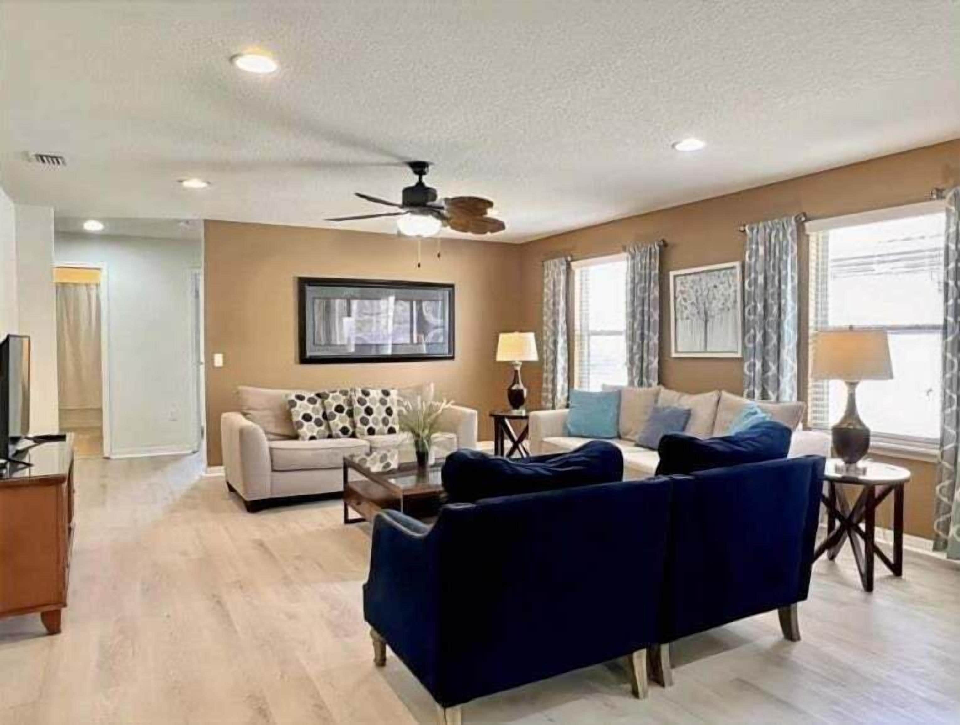 A living room with a sofa, a coffee table, a TV, and a ceiling fan.