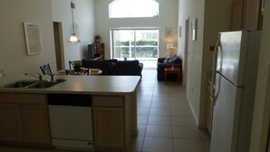 A spacious kitchen with a central island, a dining area with a sofa, and a refrigerator. - Tm148or 4 Bedroom Home by RedAwning (Davenport)