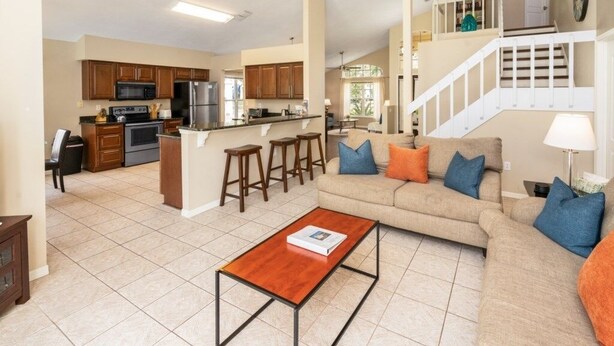 A spacious living area with a sofa, coffee table, and kitchen in the background. - Wr001or 4 Bedroom Home by RedAwning (Davenport)