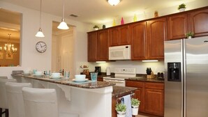 A modern kitchen with wooden cabinets, stainless steel appliances, and a central island with bar stools. - Vista Cay Gem 3 Bedroom Condo by RedAwning (Orlando)