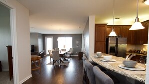 A modern kitchen with a granite countertop, stainless steel appliances, and pendant lighting. - Vista Cay Dream 3 Bedroom Home by RedAwning (Orlando)