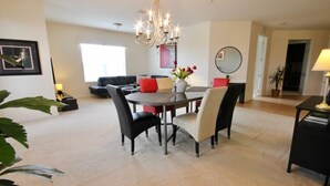 A modern living room with a dining area, featuring a chandelier, a round table, and comfortable seating.