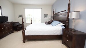 A bedroom with a large bed, dark wooden dresser, and a nightstand with a lamp. - 7-301 3 Bedroom Condo by RedAwning (Orlando)