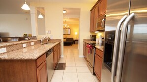 A modern kitchen with granite countertops, stainless steel appliances, and wooden cabinets. - 7-301 3 Bedroom Condo by RedAwning (Orlando)