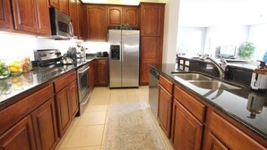A modern kitchen with wooden cabinets, stainless steel appliances, and a black countertop. - Lakeview Fantasy New! 3 Bedroom Condo by RedAwning (Orlando)