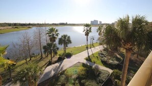A view of a lake with palm trees and a pathway leading to a building. - Lakeview Fantasy New! 3 Bedroom Condo by RedAwning (Orlando)