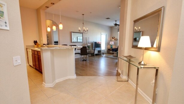 A spacious kitchen with a central island, a dining area with chairs, and a living room with a sofa and TV.