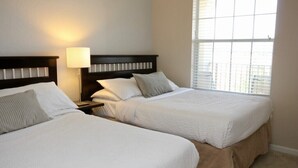 A hotel room with two beds, a nightstand, a lamp, and a large window.
