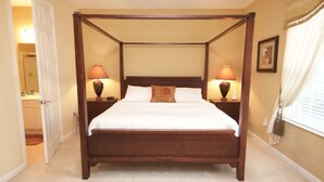 A four-poster bed with white bedding, two bedside lamps, and a nightstand on each side. - 12-103 3 Bedroom Home by RedAwning (Orlando)