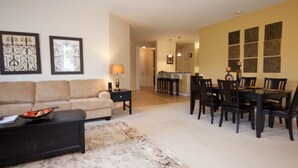 A living room with a sofa, coffee table, and dining area with chairs and a table. - 12-103 3 Bedroom Home by RedAwning (Orlando)