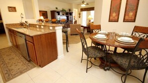 A spacious kitchen with granite countertops, a dishwasher, and a dining area with a round table and chairs.