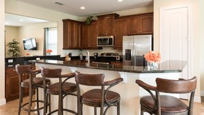 A modern kitchen with dark wooden cabinets, stainless steel appliances, and a central island with bar stools.