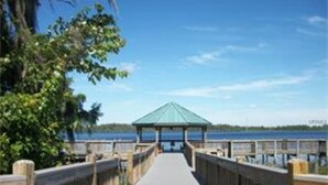 A wooden boardwalk leading to a gazebo by a lake.